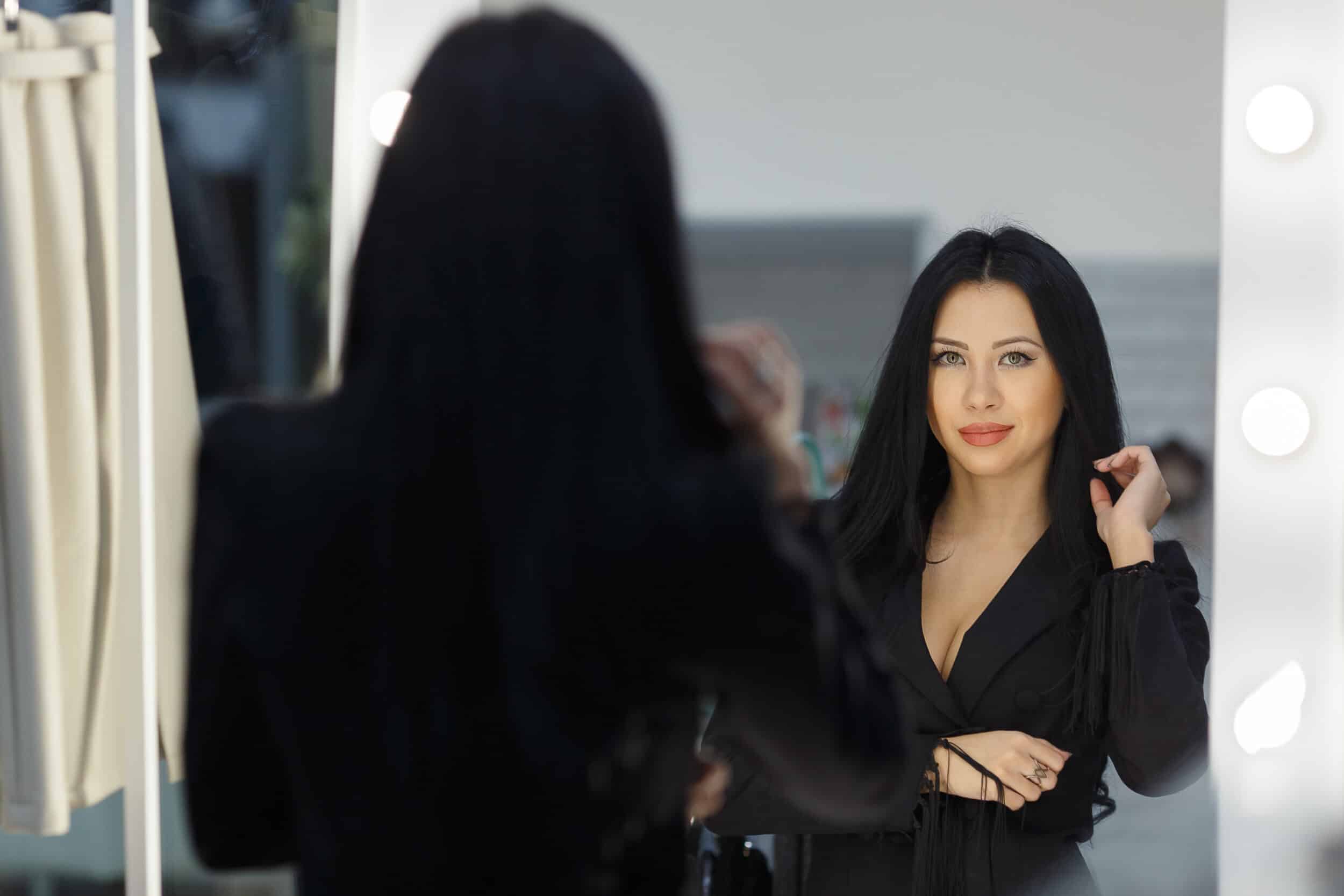 Beautiful young woman looks after a dress near a mirror Hair Smoothing Treatments in Bonita Springs, FL