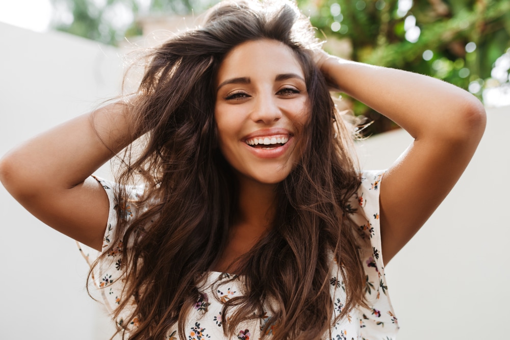 Young,Woman,Laughs,And,Looks,Into,Camera,Against,Background,Of Hair Extensions in Bonita Springs, FL